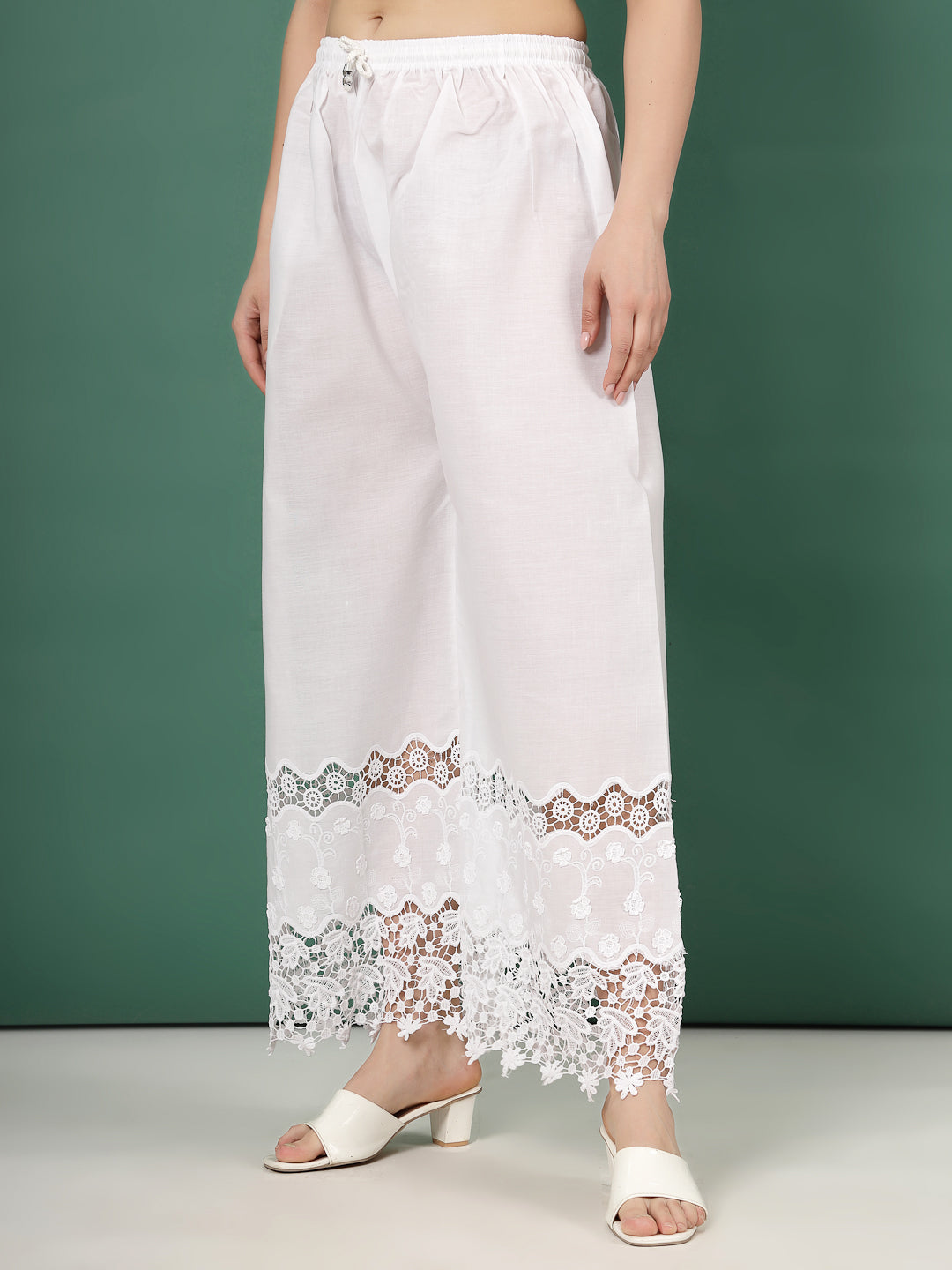 White palazzo pants with intricate lace cut work hem design.