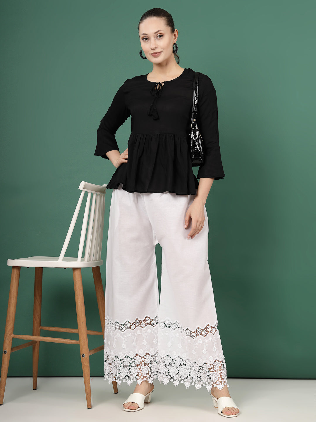 White palazzo pants with intricate lace accent and elegant cut work hem design.