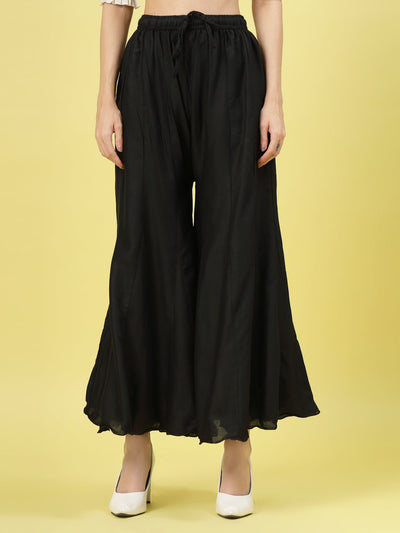 Women solid black flared rayon sharara with elasticated waistband and drawstring closure.