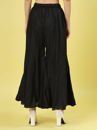 Women solid black flared rayon sharara with elasticated waistband and drawstring closure.