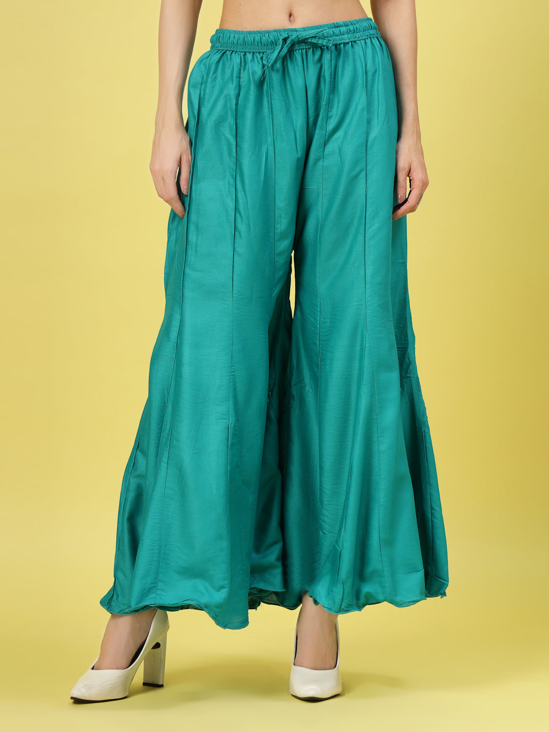 Women solid rama green flared rayon sharara with elasticated waistband and drawstring closure.