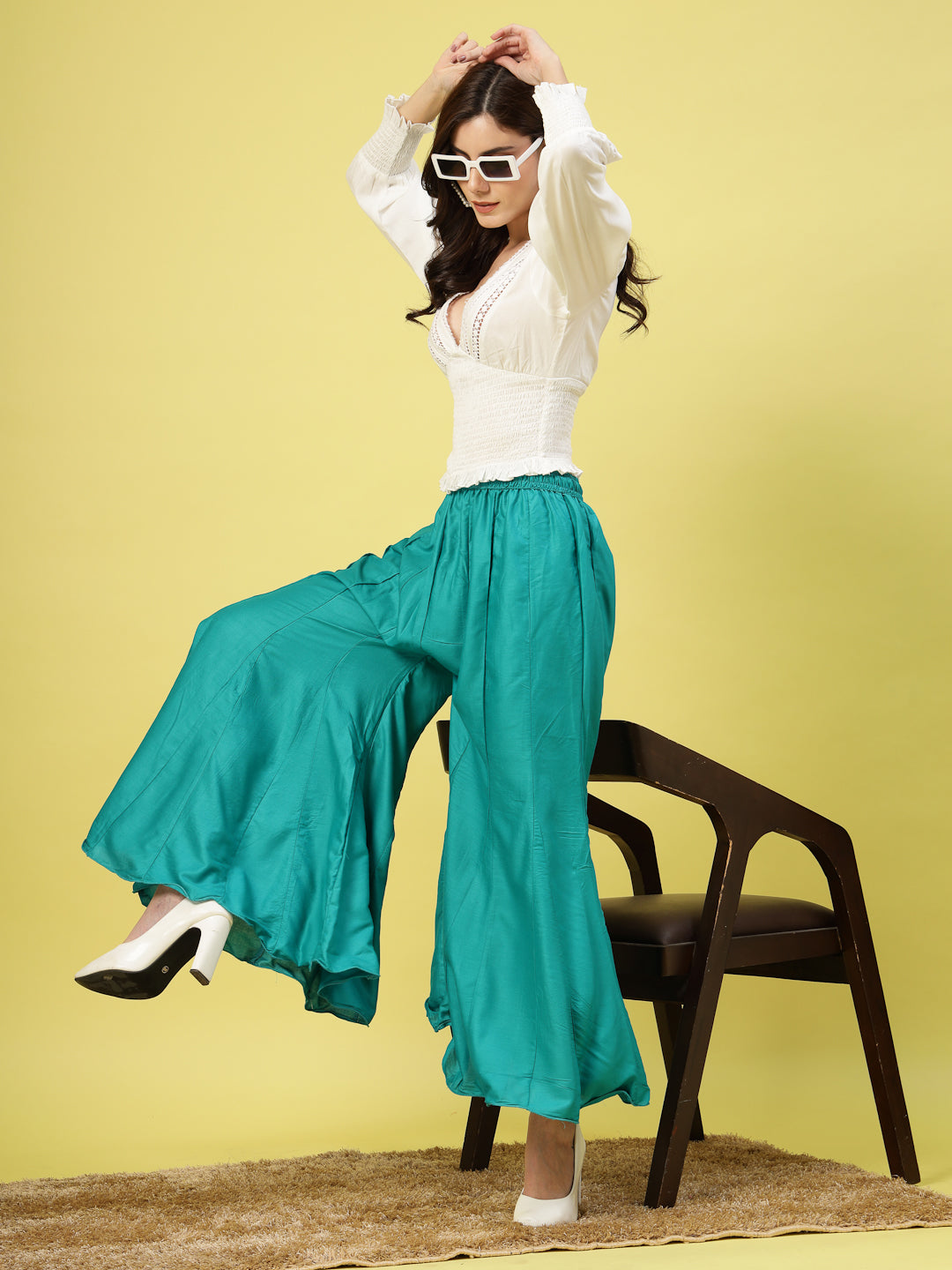 Women wearing solid rama green flared rayon sharara with elasticated waistband and drawstring closure.