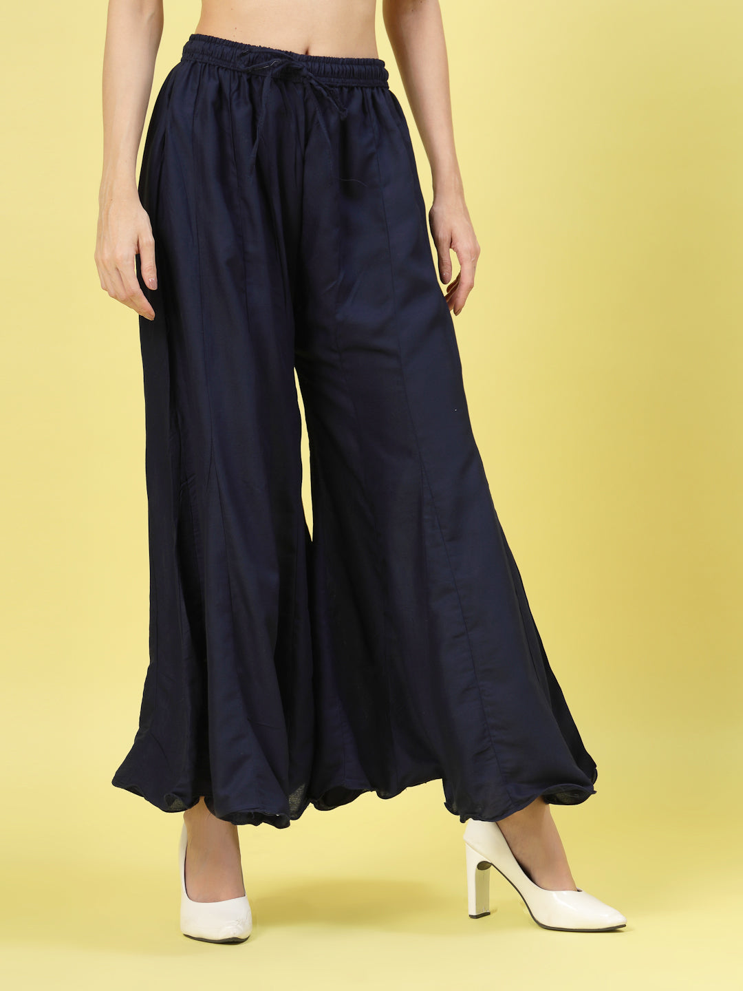 Women wearing solid navy blue flared rayon sharara with elasticated waistband and drawstring closure.