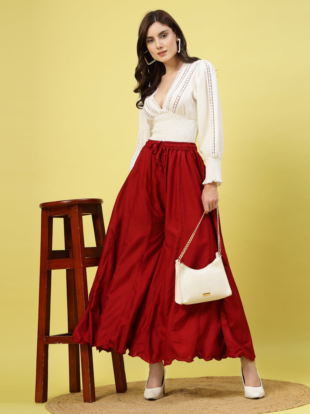 Women wearing solid maroon flared rayon sharara with elasticated waistband and drawstring closure.