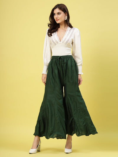 Women wearing solid bottle green flared rayon sharara with elasticated waistband.