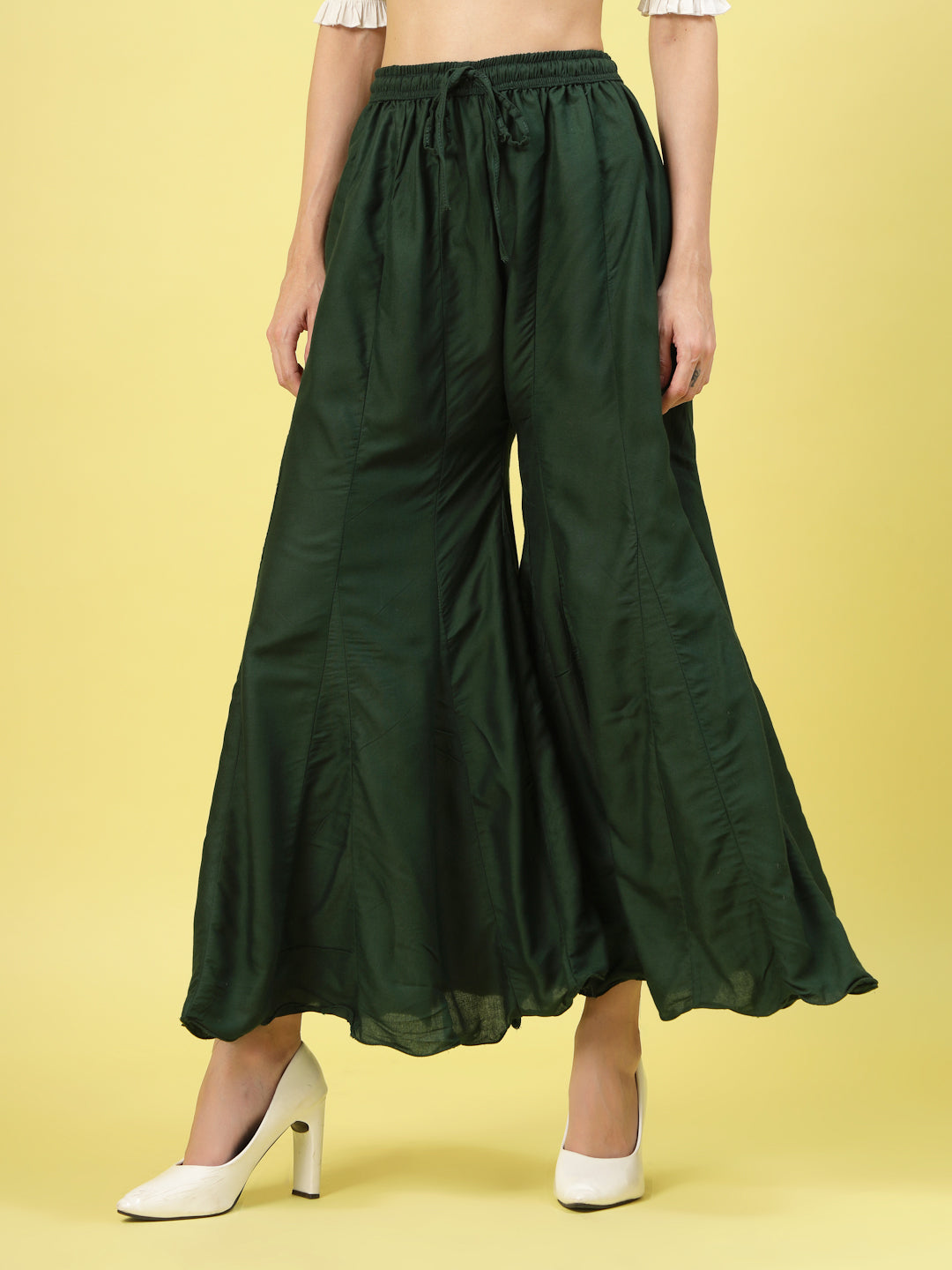 Women solid bottle green flared rayon sharara with elasticated waistband and drawstring closure.