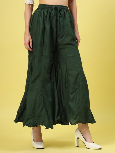 Women solid bottle green flared rayon sharara with elasticated waistband and drawstring closure.