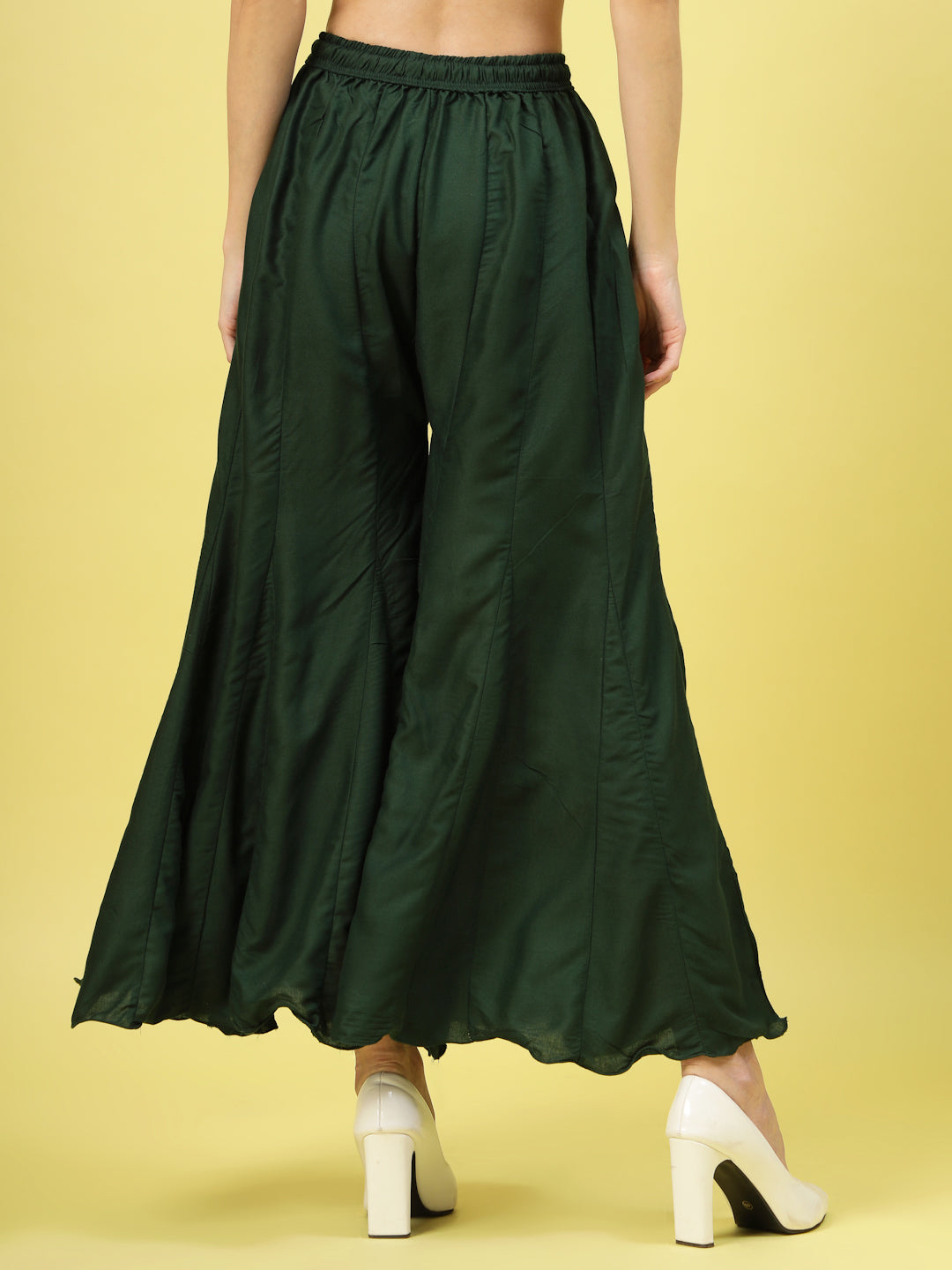 Women solid bottle green flared rayon sharara with elasticated waistband and drawstring closure.