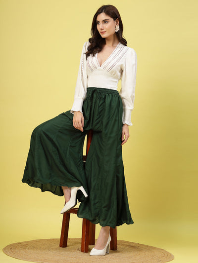 Women wearing a solid bottle green flared rayon sharara with an elasticated waistband and drawstring closure.