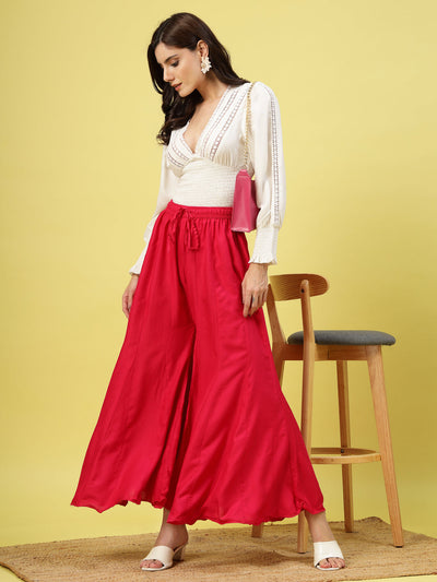 Women wearing a solid red flared rayon sharara with an elasticated waistband and drawstring closure.