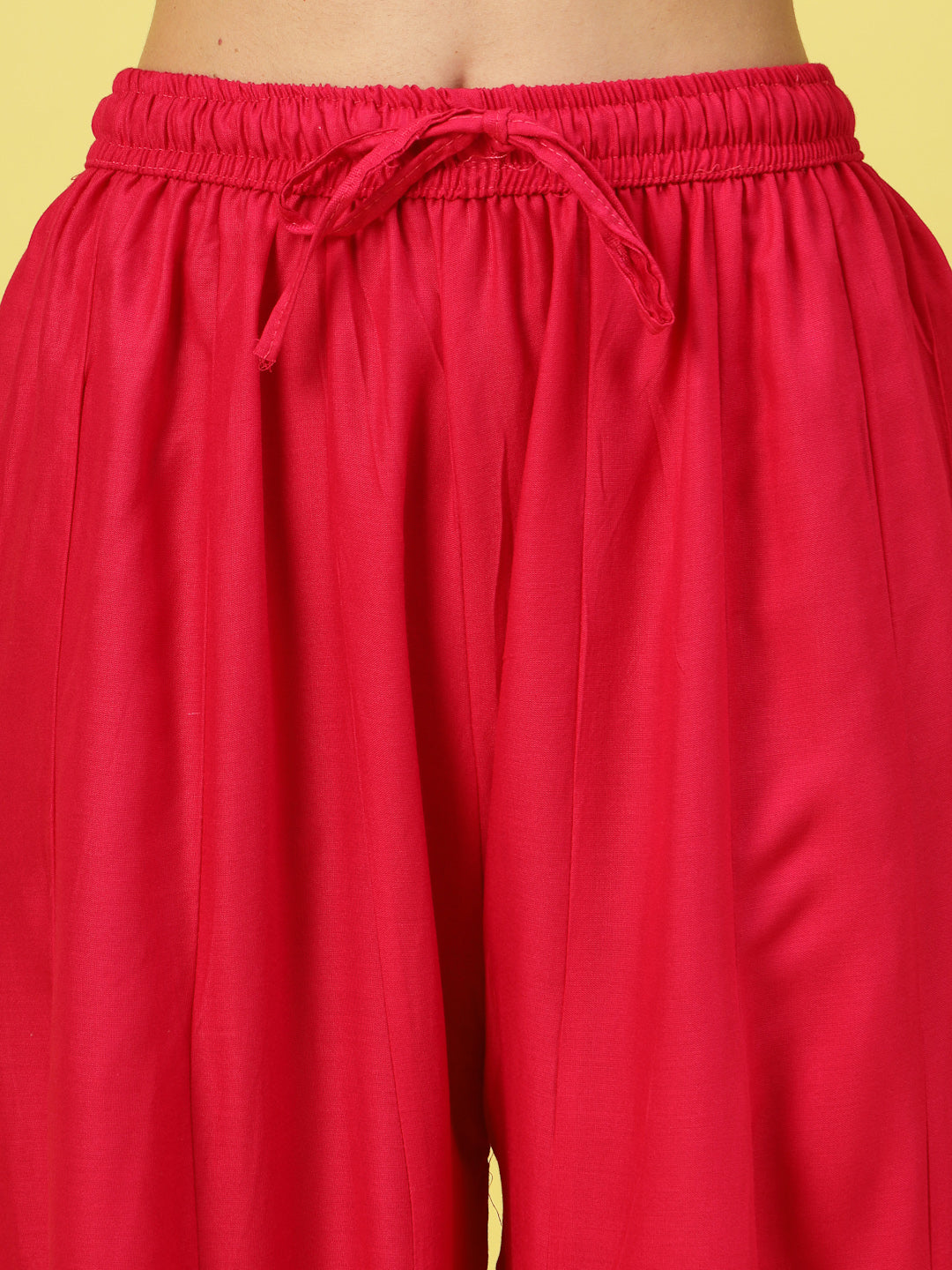 Women solid red flared rayon sharara with elasticated waistband and drawstring closure.