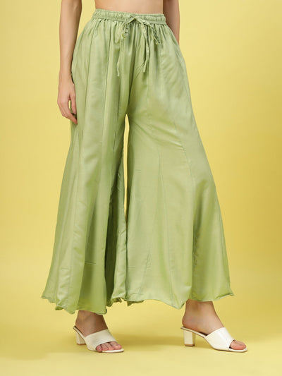 Women solid pista green flared rayon sharara with elasticated waistband and drawstring closure.