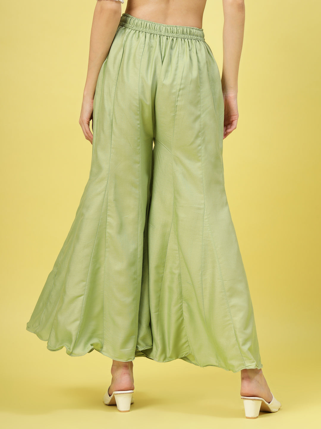 Women solid pista green flared rayon sharara with elasticated waistband and drawstring closure.