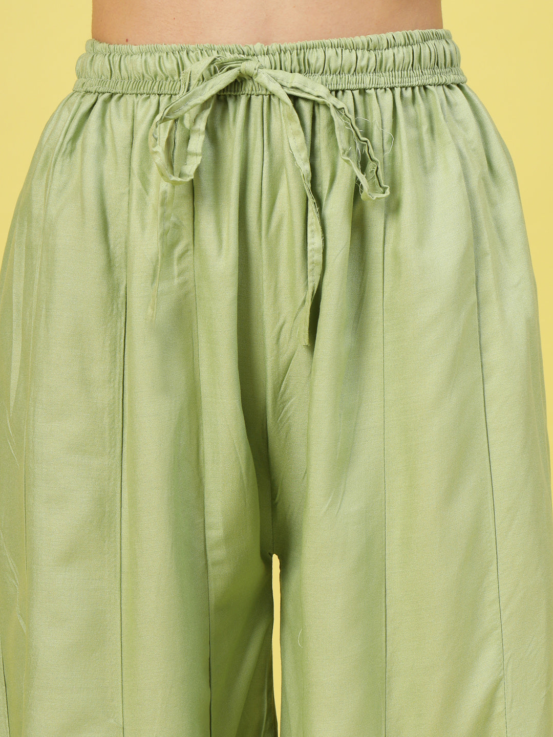 Women solid pista green flared rayon sharara with elastic waistband and drawstring closure.