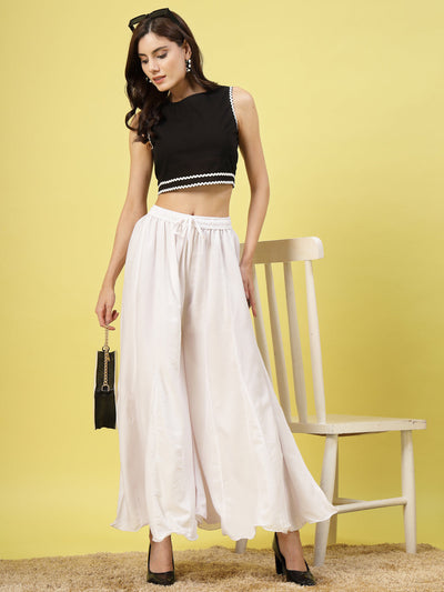 Women wearing solid white flared rayon sharara with elasticated waistband and drawstring, styled with a black top.