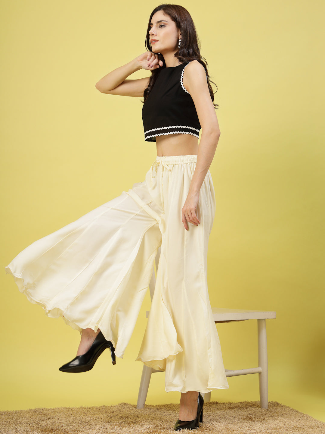 Women wearing solid cream flared rayon sharara with elasticated waistband and drawstring closure.