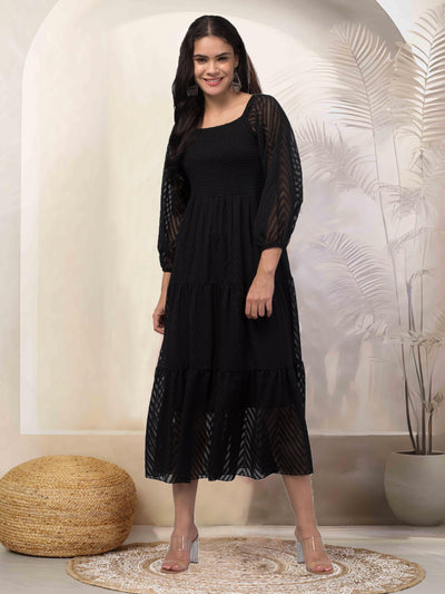 Women wearing a black printed fit and flare dress made of breathable Georgette fabric.