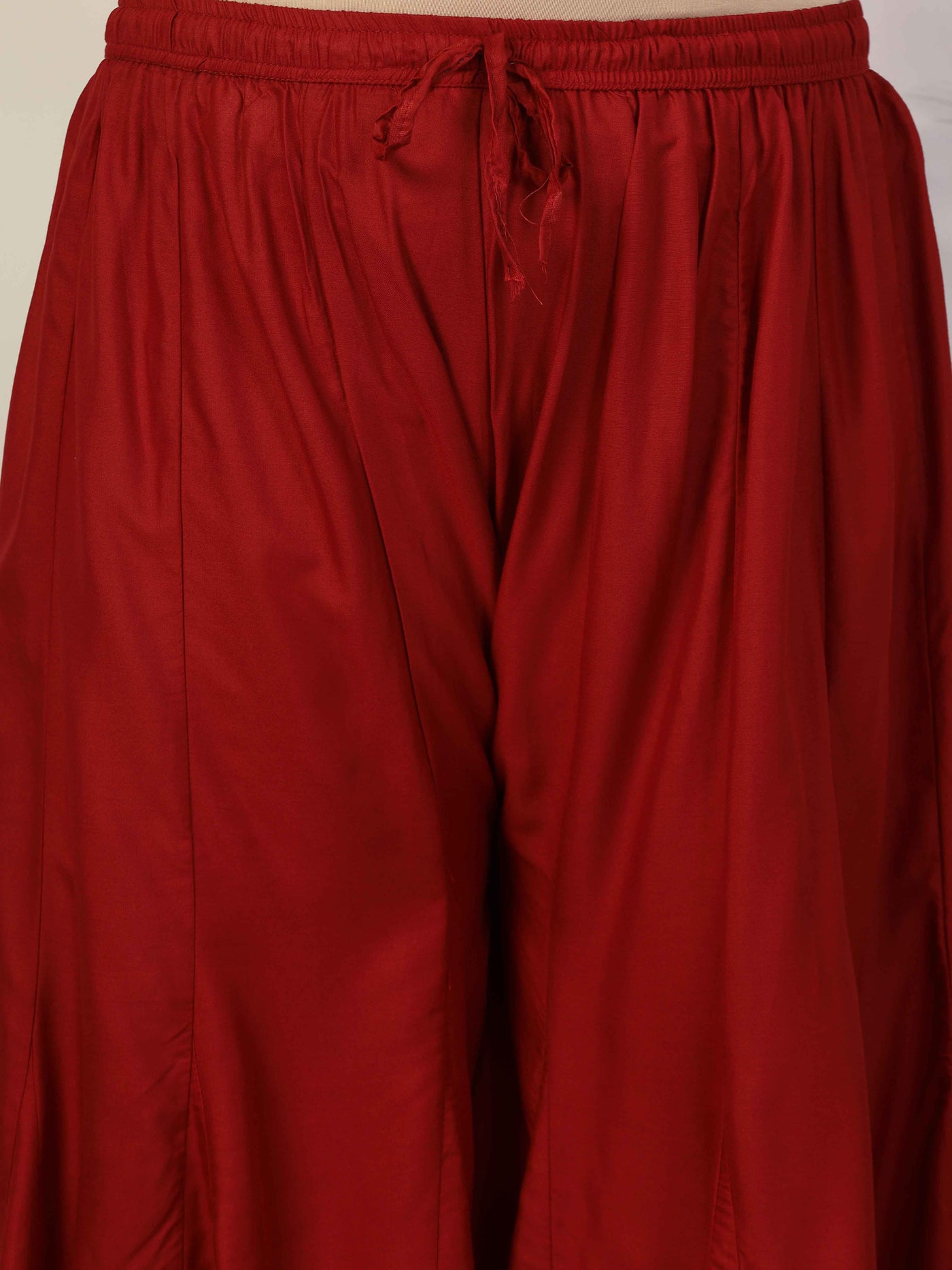 Women solid marron flared rayon sharara with elasticated waistband and drawstring closure.