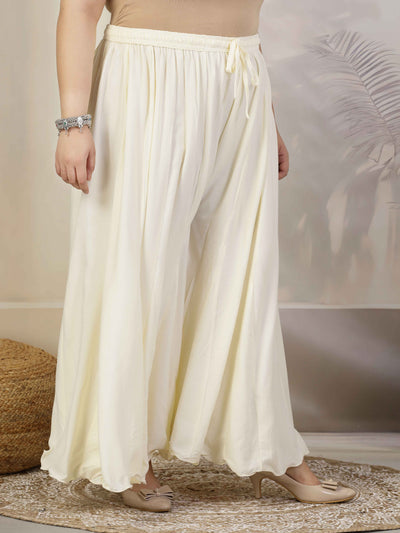 Women Solid Cream Flared Rayon Sharara with elastic waistband and drawstring closure.