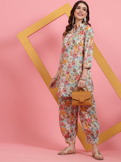 Women wearing printed cotton co-ords with embroidered tunic and Afghani trousers against a pink background.